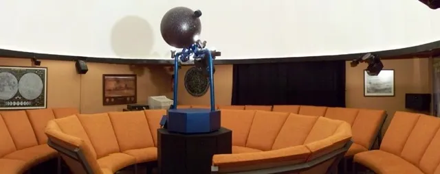 Interior del Planetario de Úbeda: butacas circulares alrededor del proyector bajo la cúpula